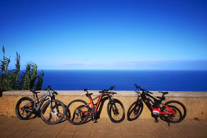 E-bikes parked against a scenic ocean view on Madeira's North Coast, ideal for an adventurous guided cycling tour experience.