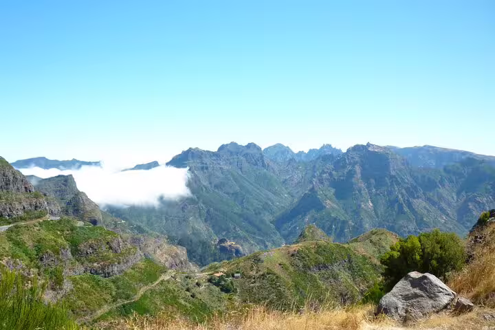 Panoramic view of Madeira's rugged mountain landscape with lush greenery and low-hanging clouds.