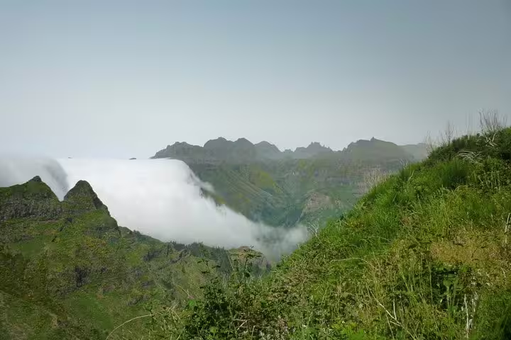 Majestic Madeira Island mountain landscape with lush greenery and clouds cascading over peaks, perfect for a scenic tour.