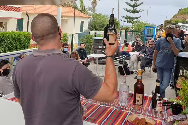 Tourists enjoy a rum tasting experience during a full day guided tour in Madeira Islands, highlighting local culture and flavors.