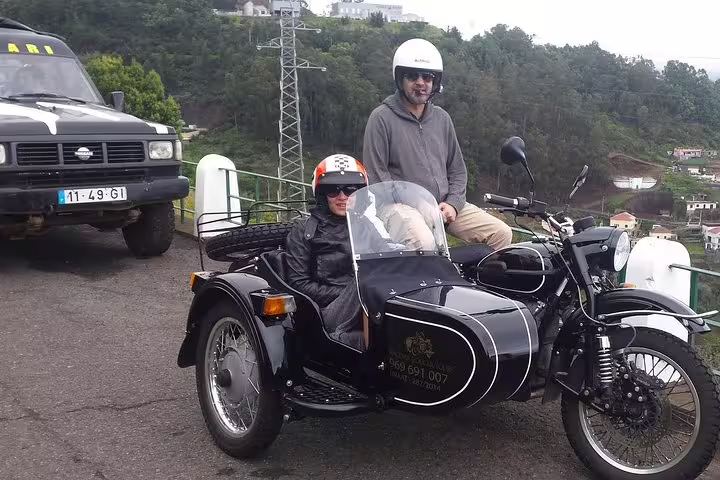 Tourists enjoy a scenic Madeira adventure on a vintage sidecar and jeep, exploring lush landscapes and breathtaking views.