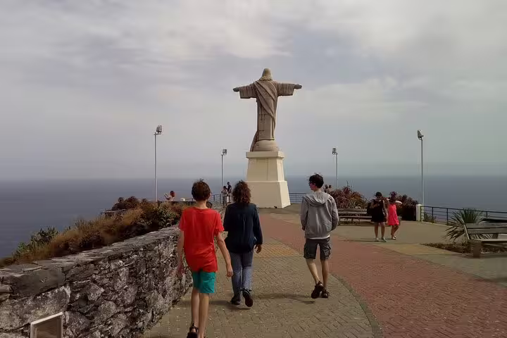 Tourists explore a scenic viewpoint with a Christ the Redeemer statue in Madeira on a sidecar and jeep adventure.