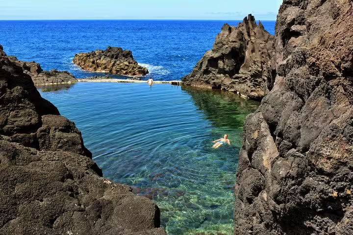 Crystal-clear natural pool surrounded by rugged volcanic rocks along the scenic Madeira coastline, ideal for 4x4 adventure tours.