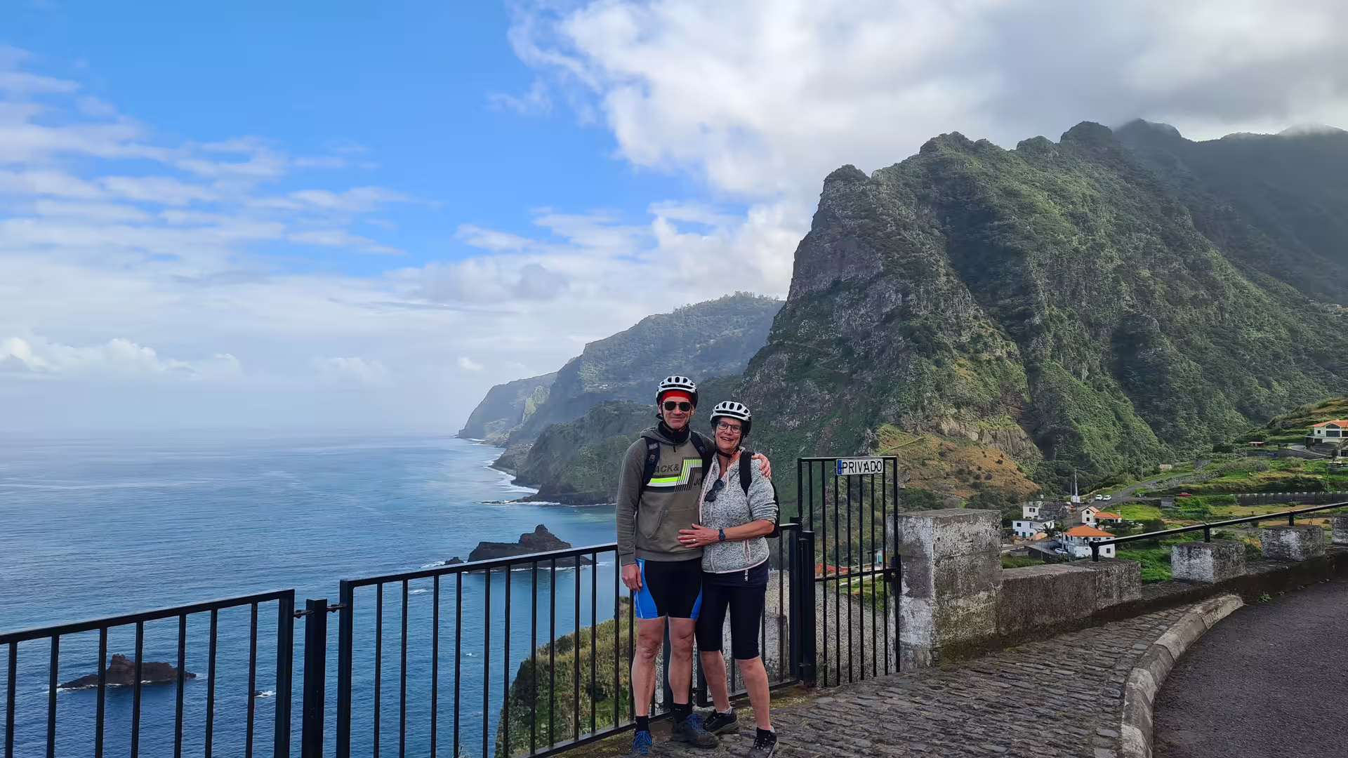 Couple enjoying a scenic guided e-bike tour along Madeira's stunning north coast, with breathtaking ocean and mountain views.
