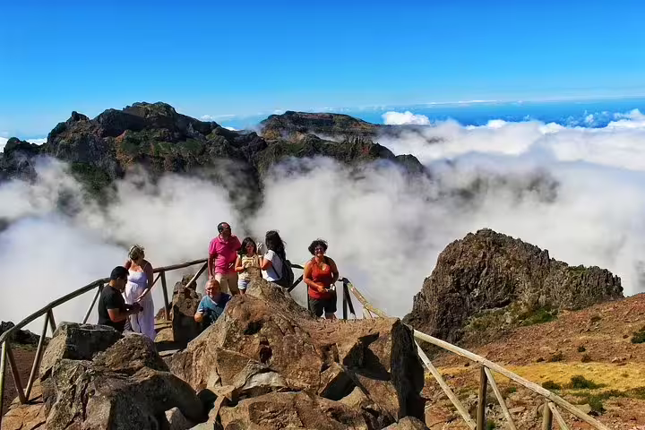 Group enjoying breathtaking views on Madeira Peaks 4X4 tour, surrounded by clouds and rugged mountains, certified "Clean & Safe".