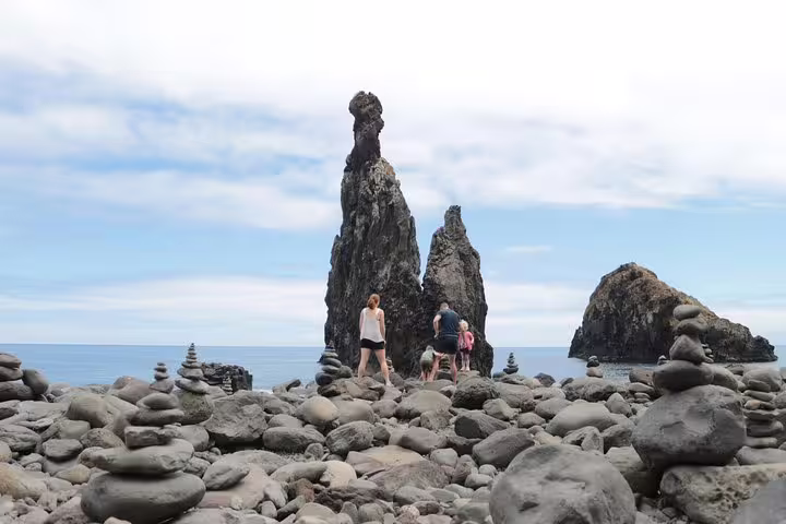 People exploring rocky beach formations on Madeira's coastline during an open-top jeep tour to Fanal UNESCO site.