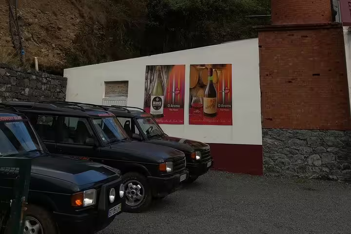 Parked safari jeeps ready for adventurous tours on Madeira's east side, showcasing local wine advertisements on the wall.