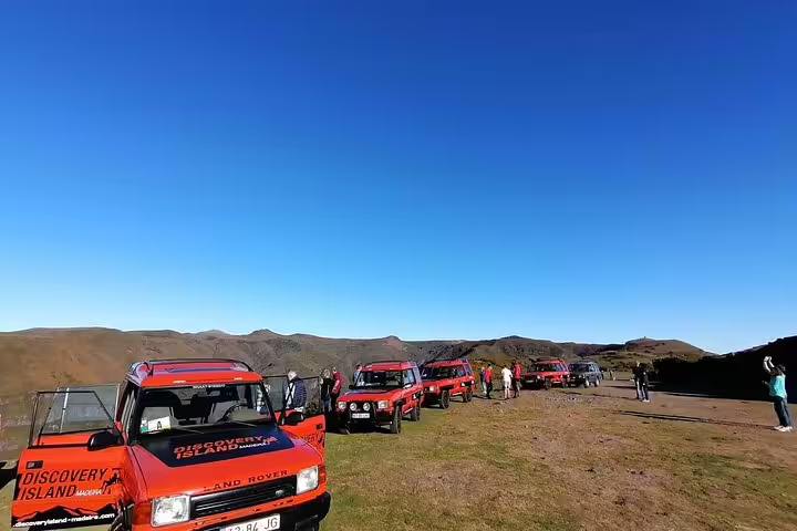 Red Land Rover vehicles lined up on a scenic plateau during Madeira safari tour on the island's west side.