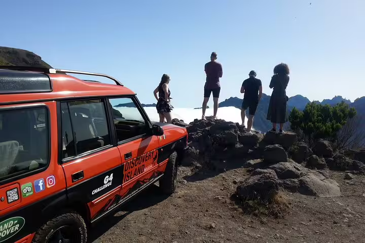 Tourists admire stunning Madeira views on a safari adventure, with an off-road vehicle poised for exploration.