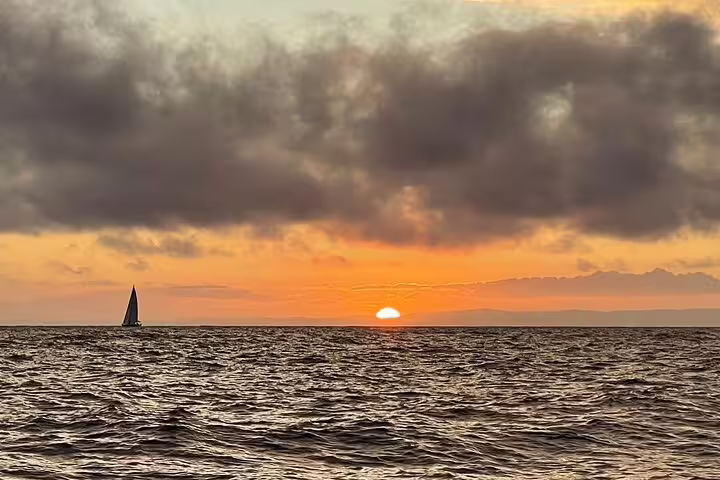 Sailboat gliding on Madeira's South Coast at sunset, offering a serene half-day sailing experience on the Atlantic Ocean.