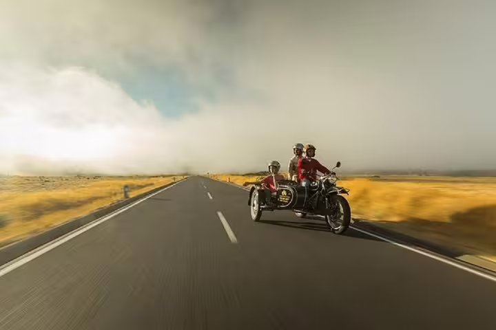 Sidecar tour on Madeira's scenic Old Road West, showcasing stunning landscapes and adventure under a dramatic sky.