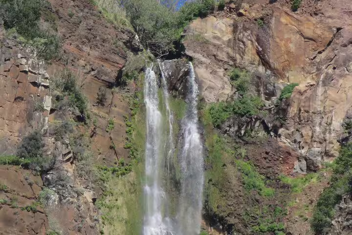 Stunning waterfall cascading down rocky cliffs surrounded by lush greenery on a guided 4x4 tour in Southwest Madeira.