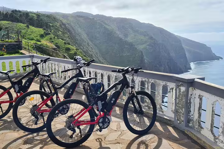 Scenic bike tour along Madeira's west coast featuring electric bikes, stunning ocean views, and lush green cliffs.