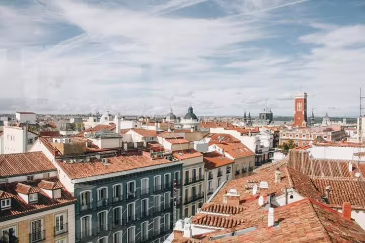 Panoramic view of Madrid's historic rooftops under a vibrant sky, perfect for a memorable rooftop bar crawl experience.
