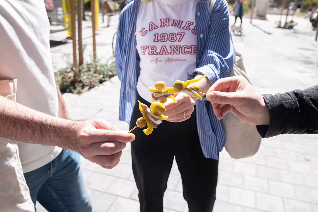 Tourists enjoy traditional Spanish tapas on a sunny street during the Authentic Madrid Food, Wine & Culture Tour.