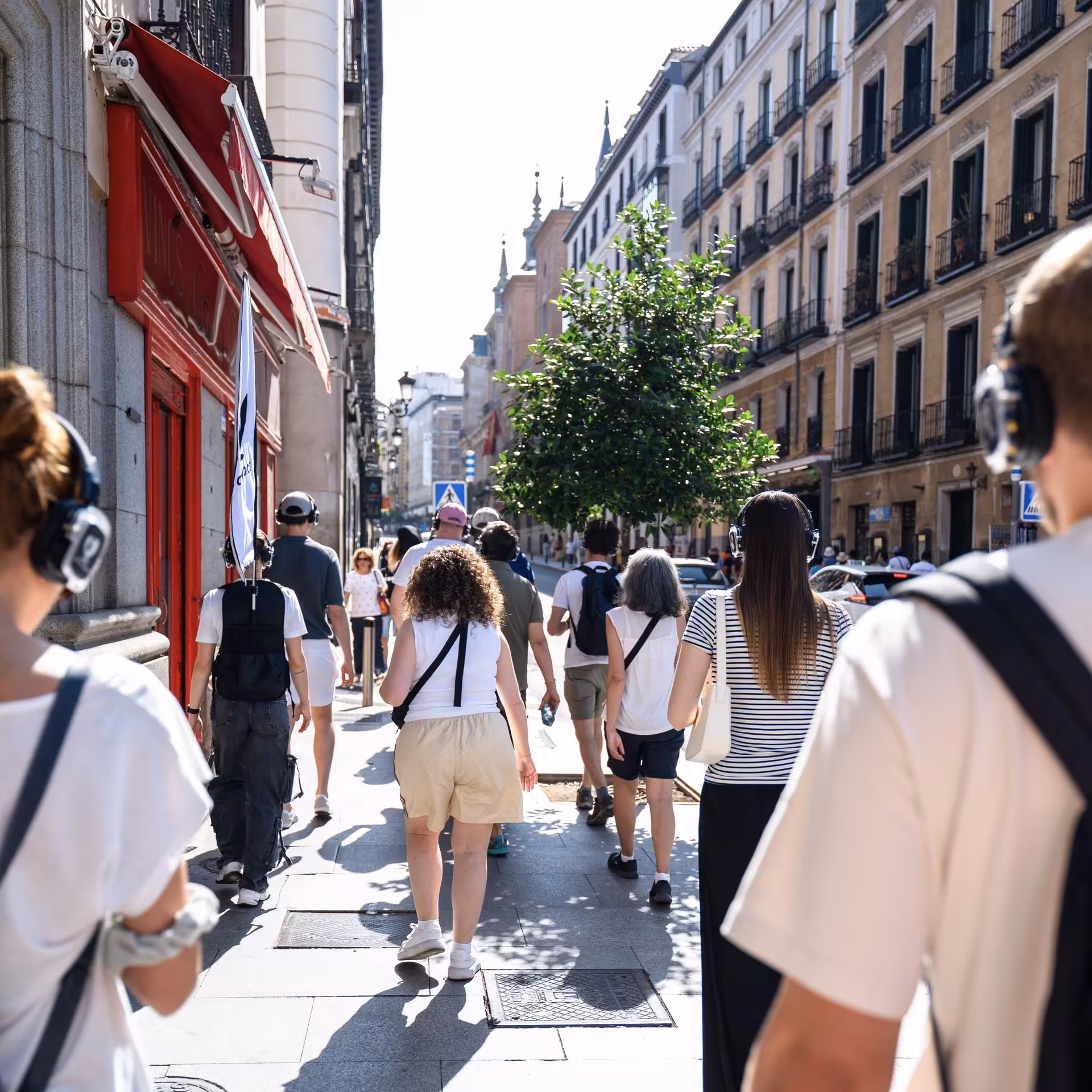 Tourists with headphones exploring lively streets of Madrid on a CityVoice walking tour for an immersive experience.