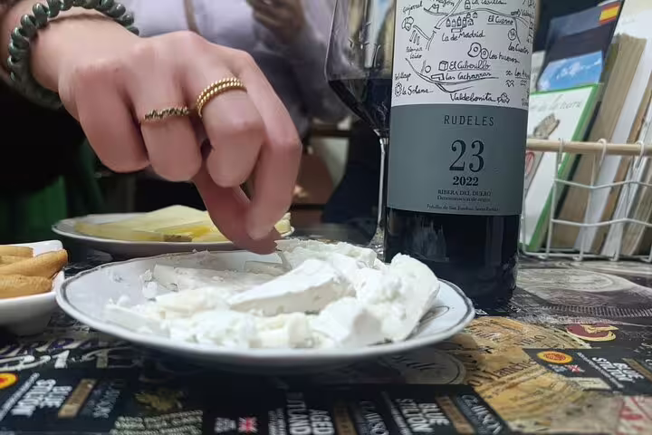 Hand selecting cheese paired with a bottle of red wine on the Madrid City Wine Tour.