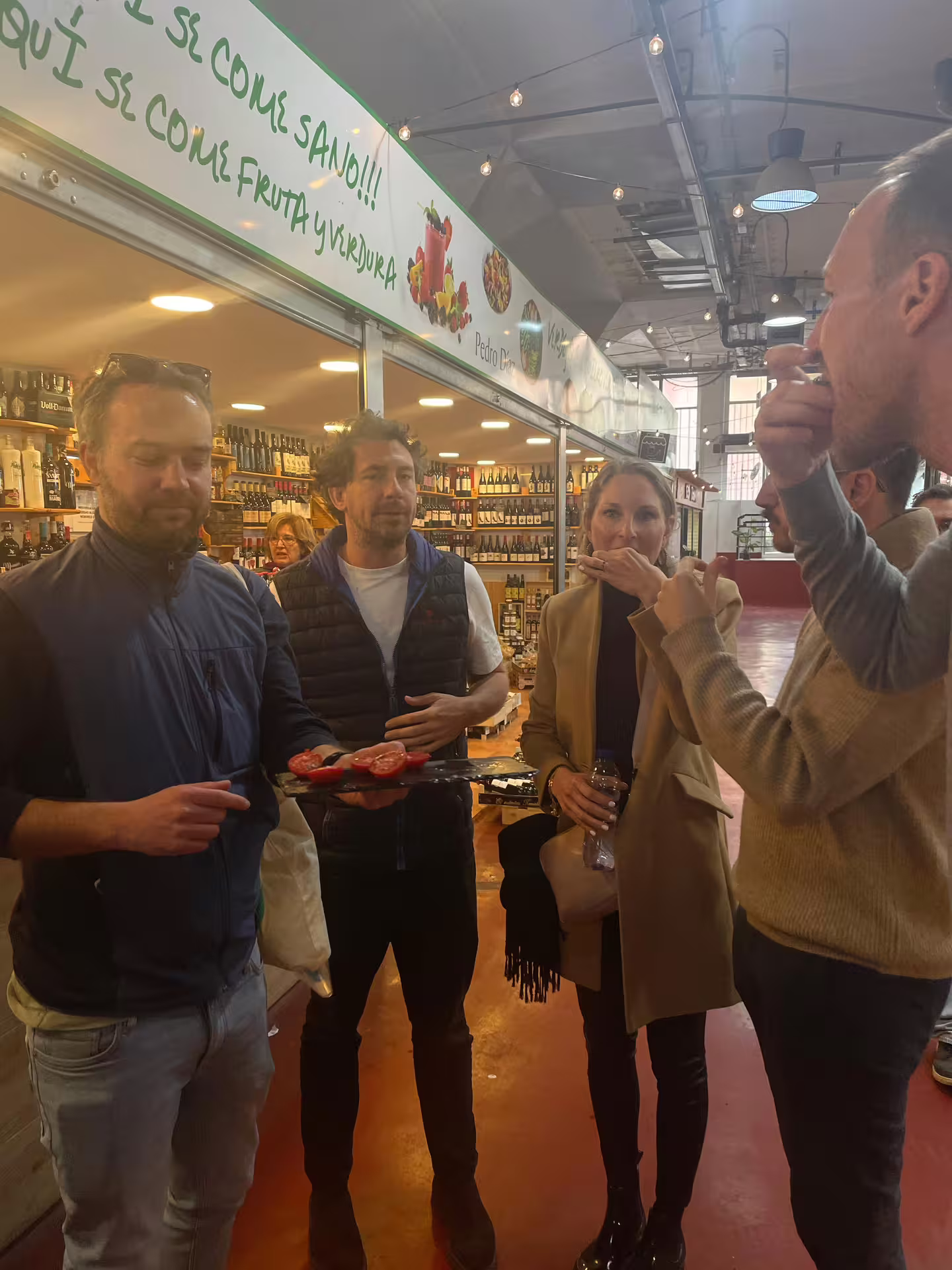 Tour group enjoying wine and tapas tasting at a vibrant Madrid market during a city wine tour.