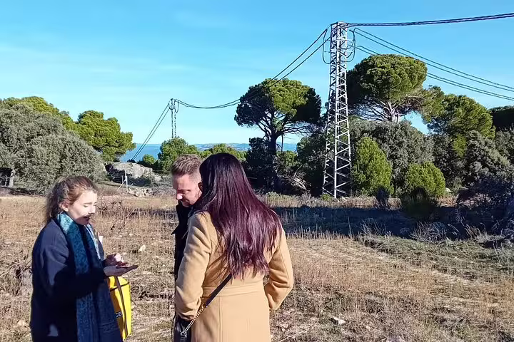 Group engages in discussion amidst Madrid's picturesque wine country, surrounded by trees and open fields.