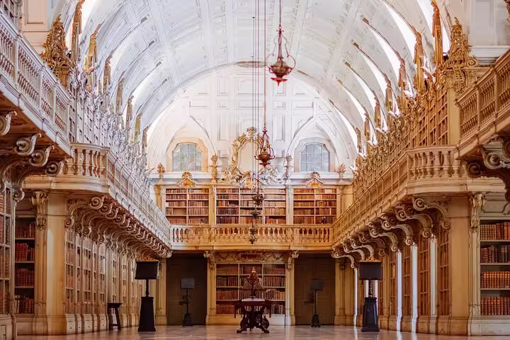 Ornate interior of Mafra Palace Library with grand wooden shelves and vaulted ceilings, featured in Lisboa small-group tour.