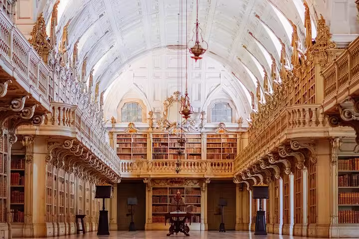 Ornate library interior at Mafra Palace, showcasing grand architecture and vast book collections on the Mafra, Ericeira & Queluz tour.