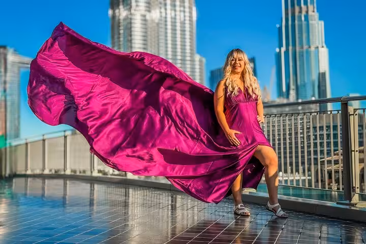Woman in a magenta flying dress poses with Burj Khalifa in background, capturing Dubai's iconic skyline for Instagram.