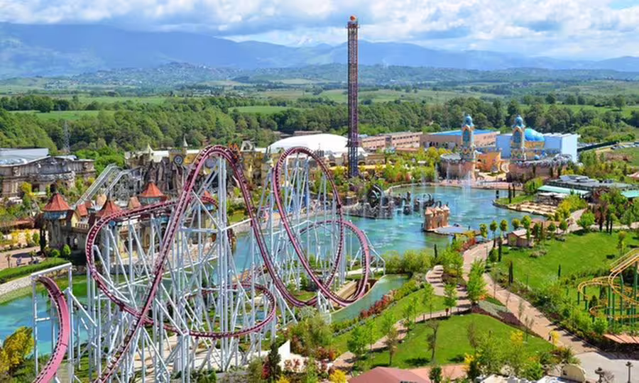 Aerial view of MagicLand theme park with looping roller coasters, water lagoon and thrill rides near Rome