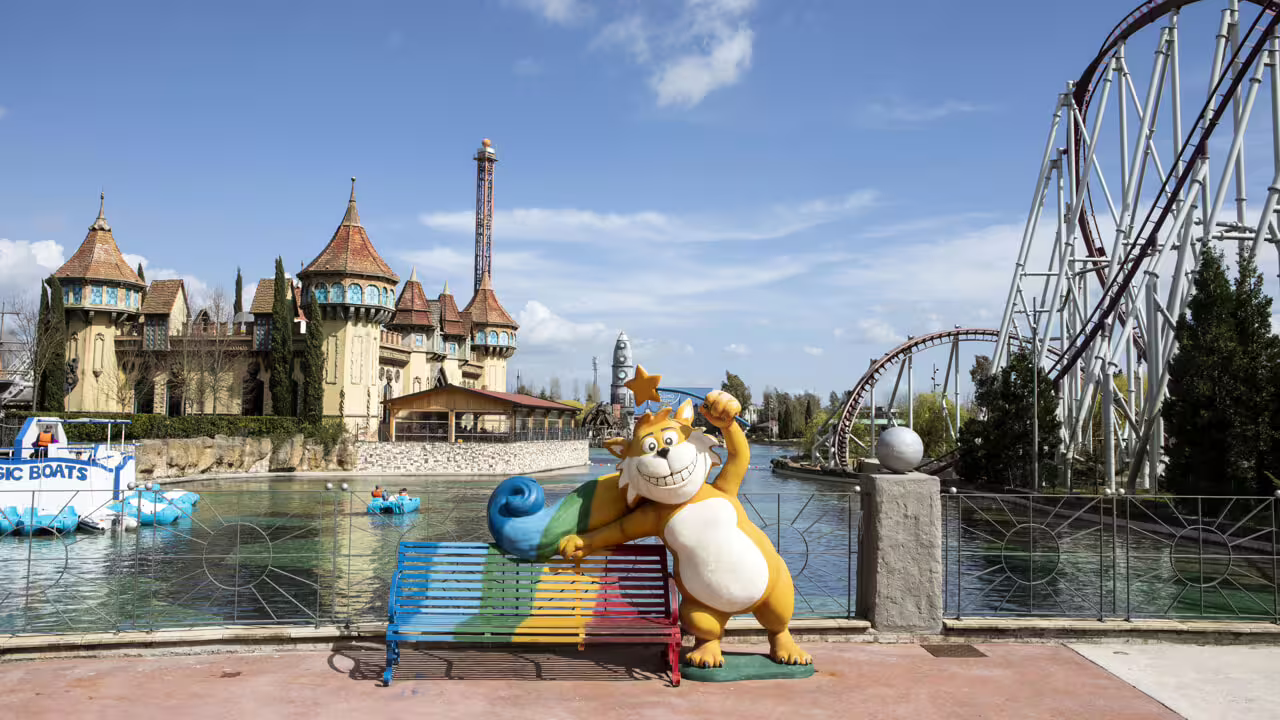 MagicLand Amusement Park lake view with castle, mascot statue and roller coaster, ideal for family day out