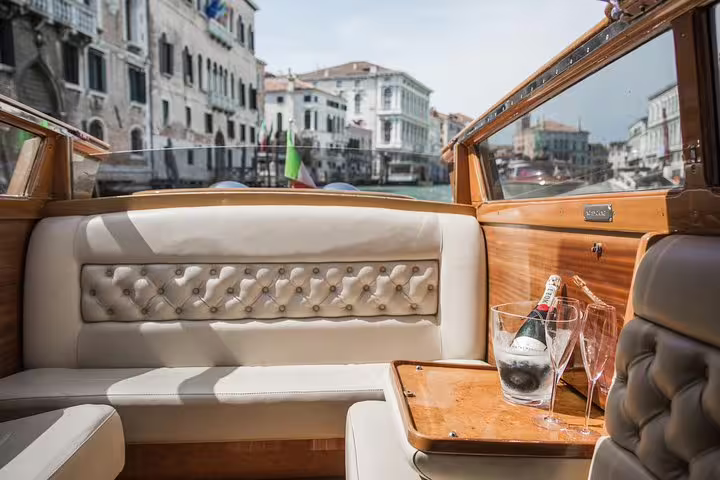 Champagne and glasses on a mahogany boat with scenic views of Venice, perfect for The Mahogany Boat Full Day Experience.