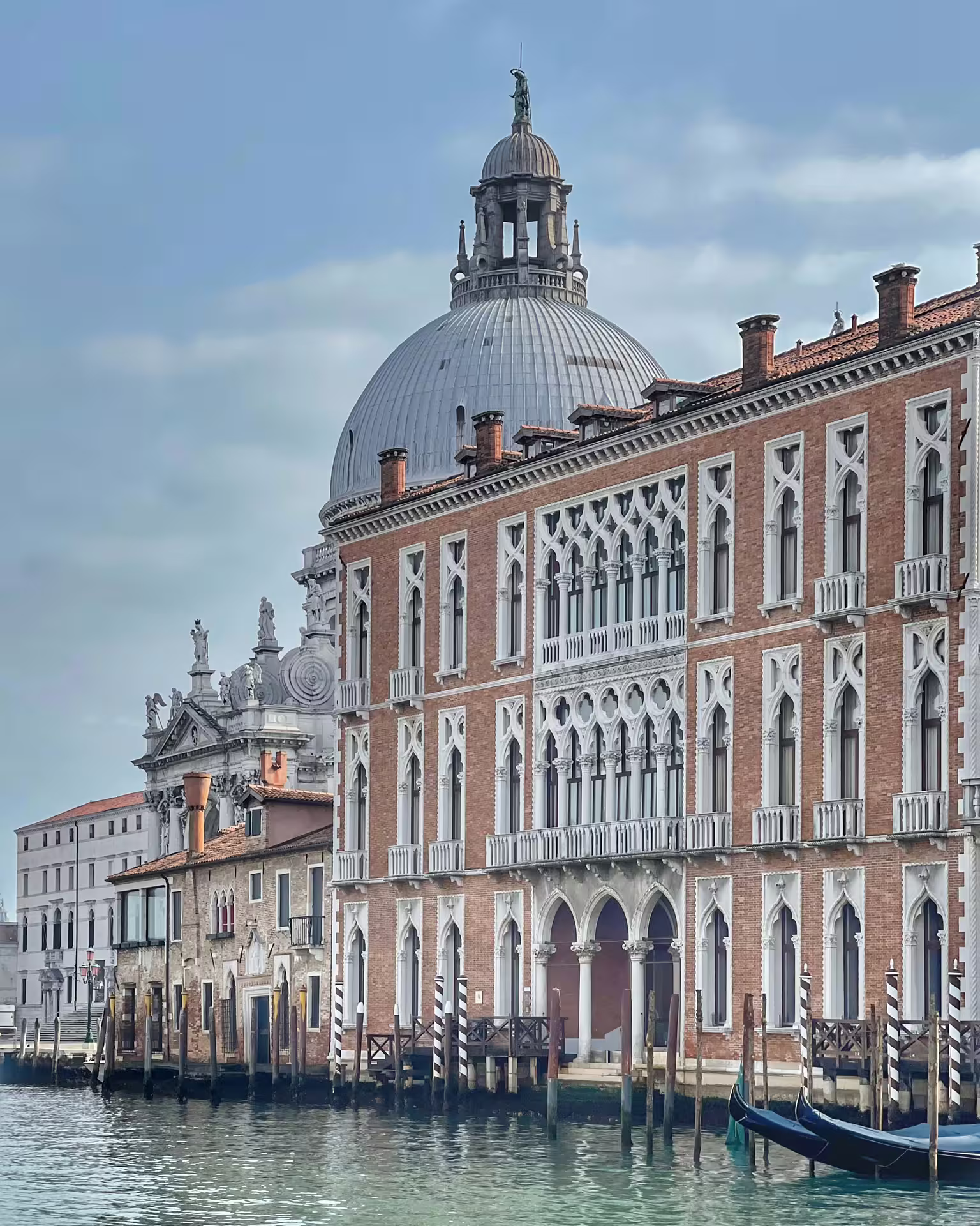 Stunning view of Venice's ornate Gothic architecture with a prominent dome along the tranquil canal waters.
