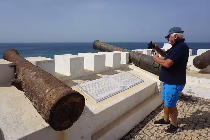Tourist capturing historic cannons at a coastal fort in Vila do Maio, offering panoramic ocean views.