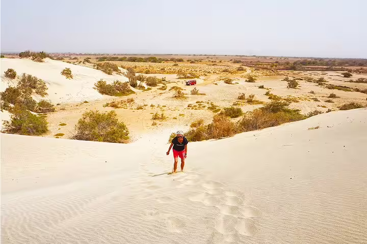Hiker climbing sand dunes on Maio Island, Cape Verde, scenic detour during private Harbour to Calheta transfer
