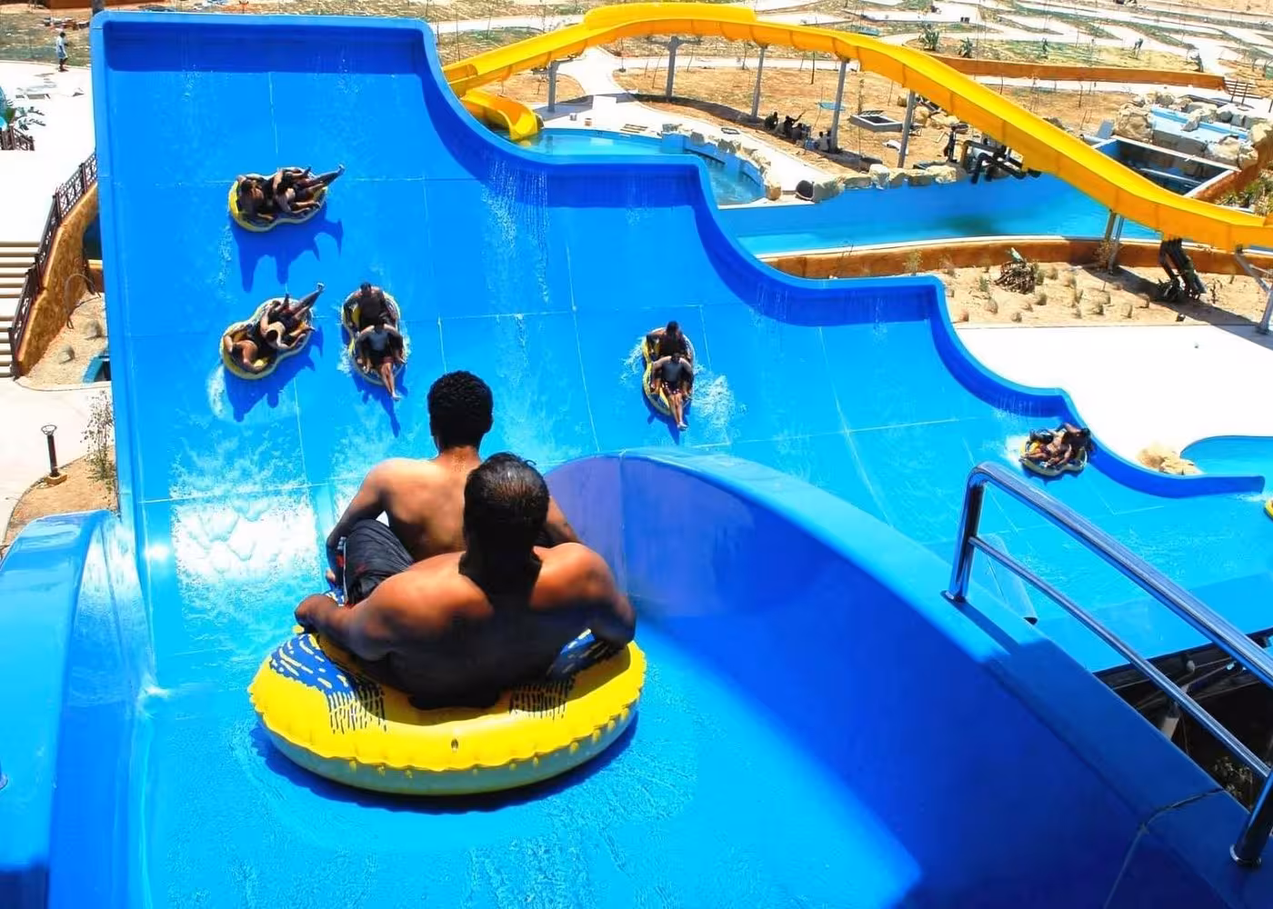 Riders on inflatable rafts racing down blue slide at Makadi Water World Aqua Park Hurghada with transfer