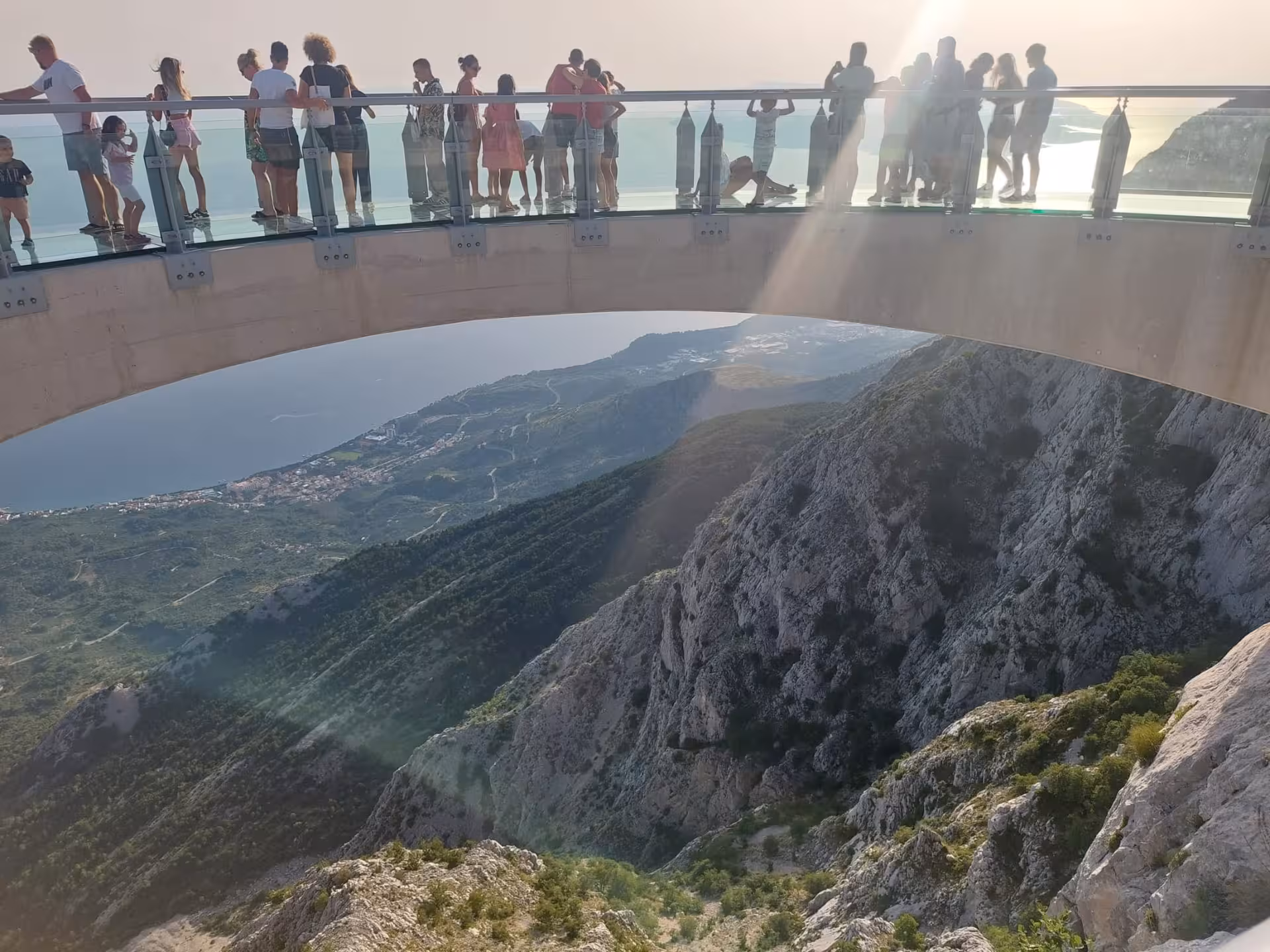 Visitors on Biokovo Skywalk glass bridge with sweeping Makarska Riviera and Adriatic views on Split day trip