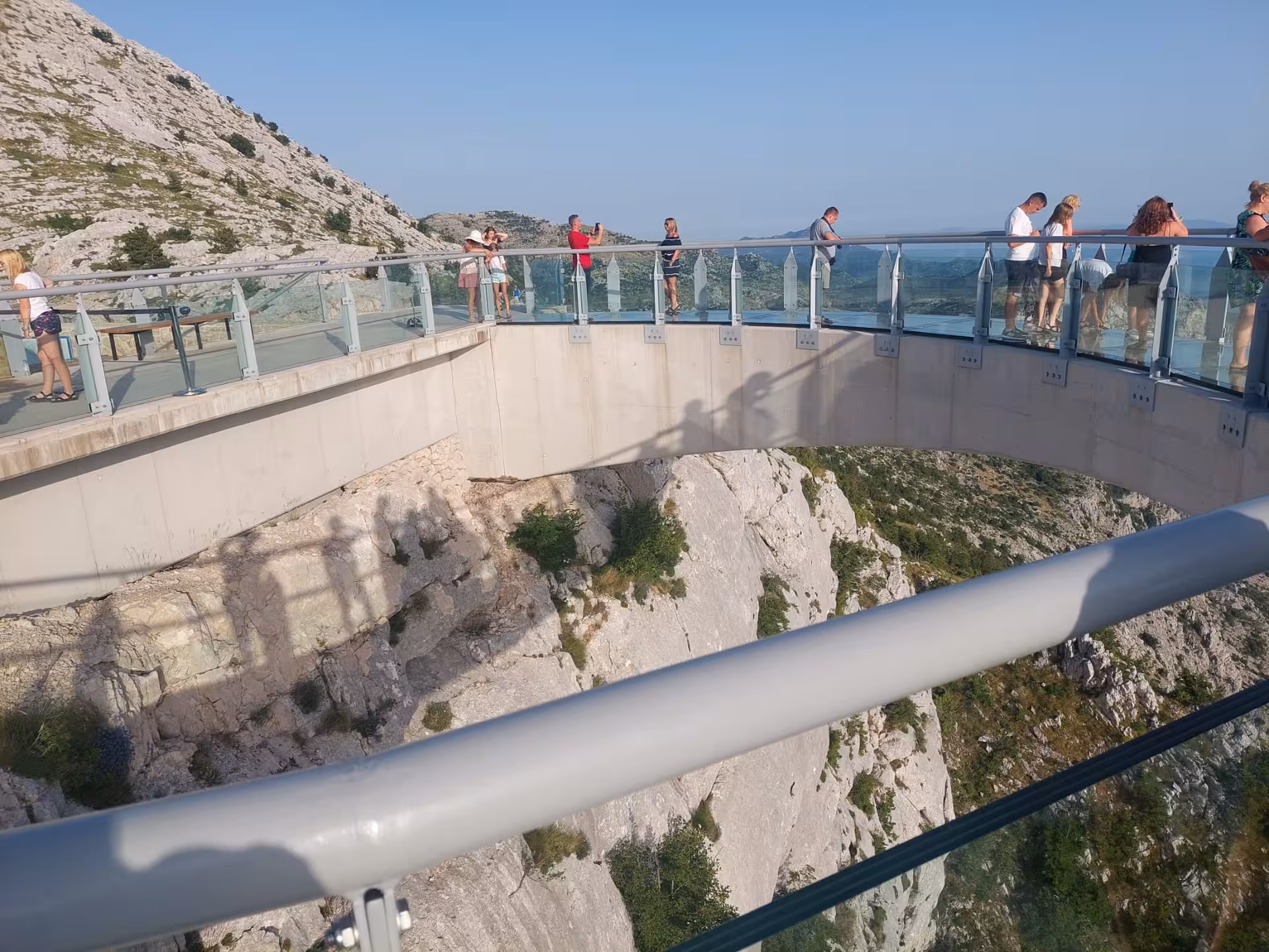 Tourists on Biokovo Skywalk glass bridge above Makarska cliffs on Split to Skyline cliffview adventure