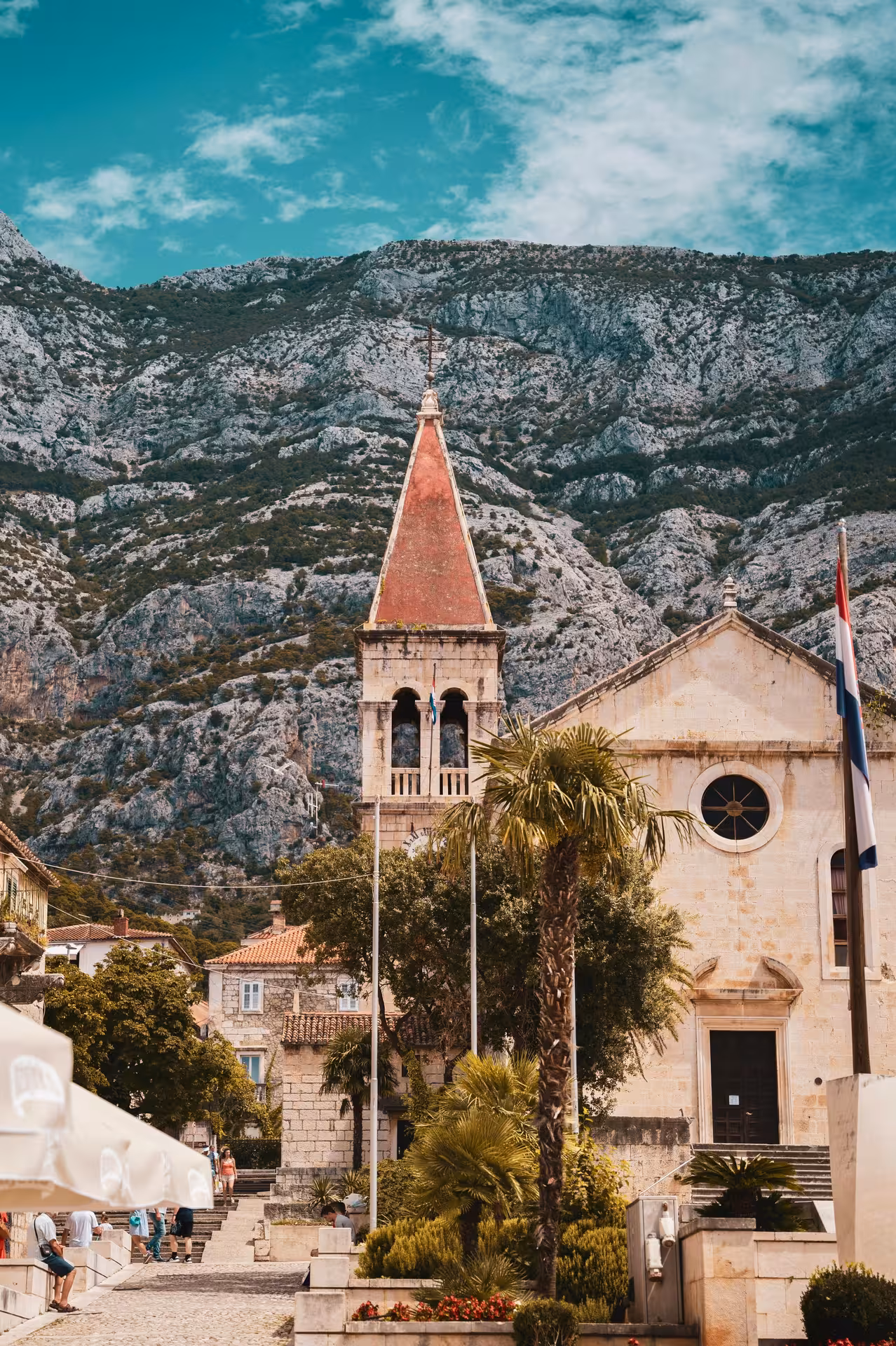 Makarska old town church and bell tower beneath Biokovo mountains on Split to Makarska cliffview adventure