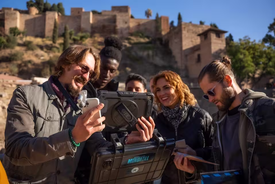 Enthusiastic group solving outdoor escape game clues in sunny Malaga near historic architecture.