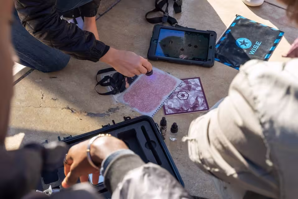 Players work together with UV light and tablets in intense Malaga BlackOut outdoor escape game challenge.