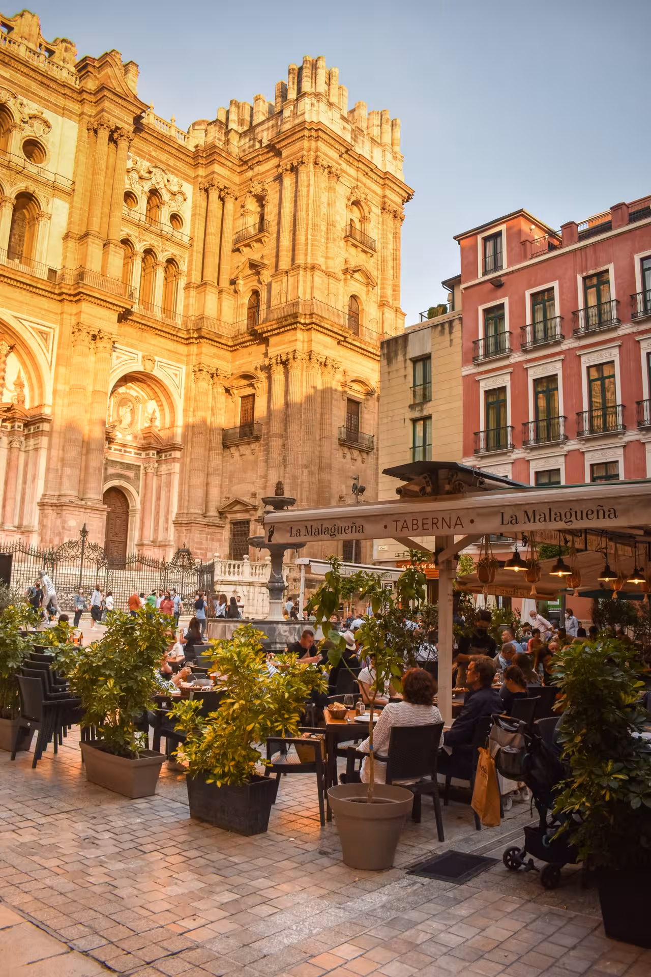 Outdoor café near the majestic Cathedral of Malaga, showcasing vibrant city life and historic architecture.