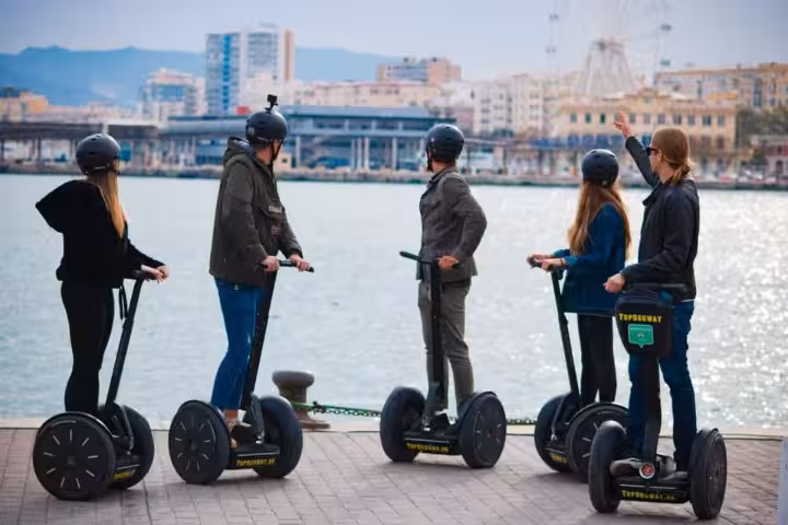 Group on Segways visiting Malaga Cathedral during a historical city tour under the sunny sky.