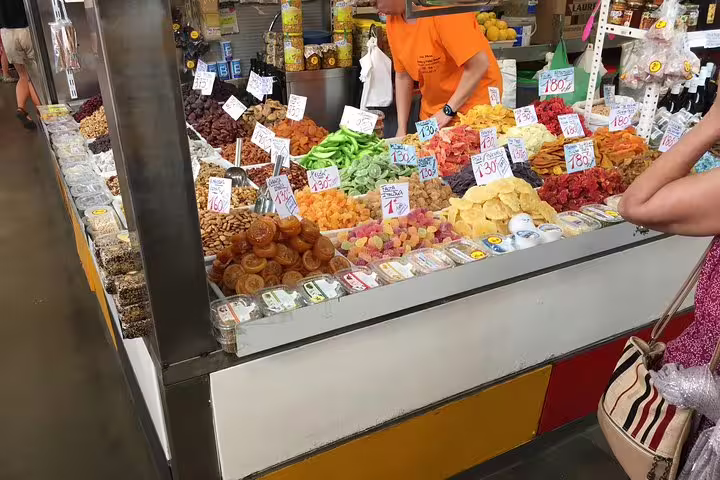 Vibrant market stall in Malaga showcasing an array of colorful dried fruits and nuts, perfect for a culinary tour.