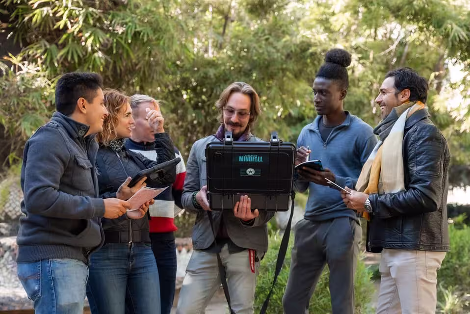Group of people enjoying the Malaga Outdoor Escape Game Operation Mindfall in a lush park setting.