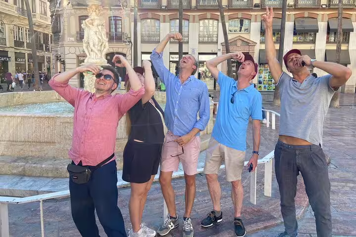 Group celebrating by Malaga Plaza de la Constitucion fountain on a self-guided scavenger hunt tour