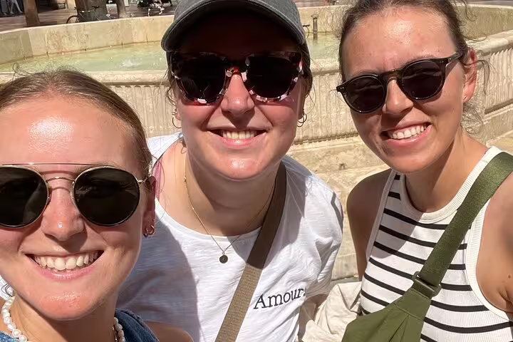 Friends smiling at a Malaga fountain during a self-guided scavenger hunt and sights walking tour