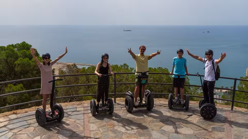 Group on Segways celebrating panoramic sea views during Malaga City Tour on a sunny day.