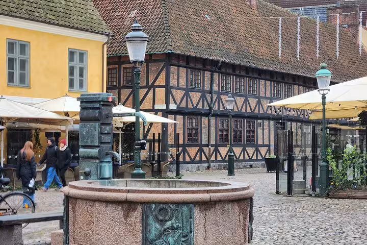 Quaint cobblestone square with traditional timber buildings and a central fountain in Malmo, ideal for sightseeing.
