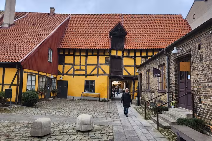 Charming historic building with vibrant yellow facade in Malmo's old town district, perfect for a cultural walking tour.