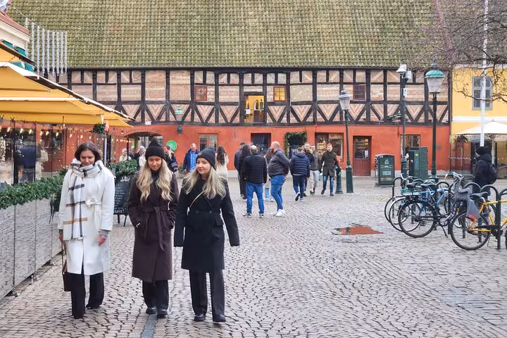 Tourists stroll through Lilla Torg, a vibrant cobblestone square in Malmo, surrounded by colorful historic buildings.