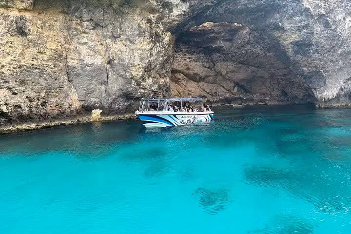 Boat cruising Malta Blue Lagoon caves in Comino, turquoise water and limestone grotto on half-day tour