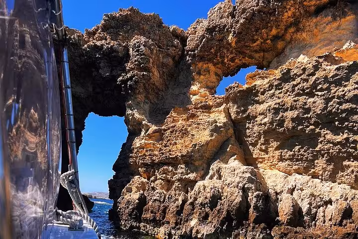 Boat passing Gozo sea arch on Half Day Malta tour to Comino Blue Lagoon caves and coastal cliffs